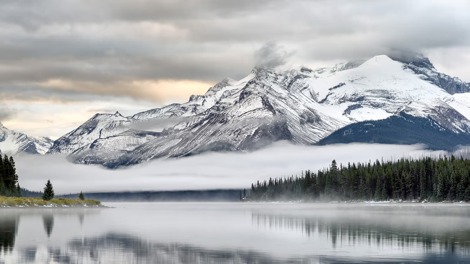 Lac de montagne paisible au petit matin, sommets enneigés se reflétant dans l'eau calme, symbole d'un avenir financier serein